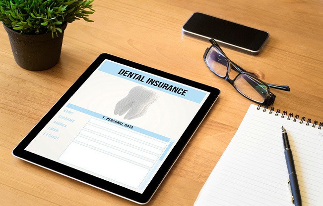 Dental insurance form on tablet on desk with notepad