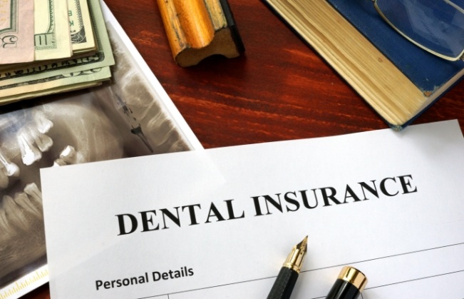Dental insurance paperwork on dark wood table