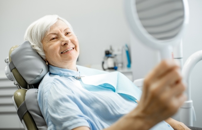 Senior dental patient admiring her smile in a mirror