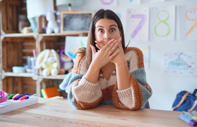 Woman in classroom covering her mouth with her hands