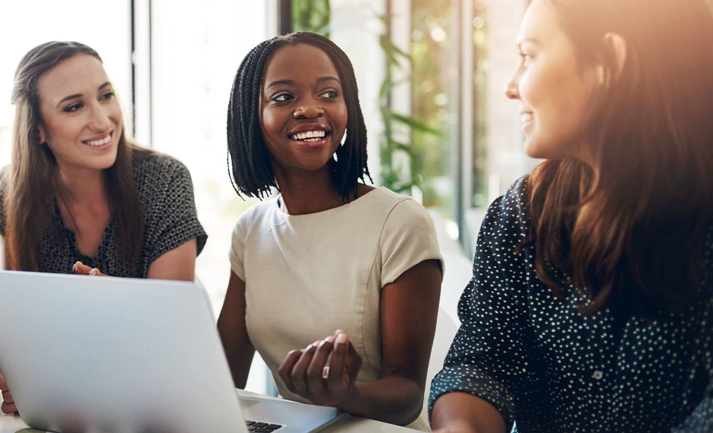 Three woman sitting at table with laptop having discussion