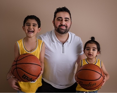 Doctor Navi Dhaliwal's husband with their two sons wearing basketball uniforms
