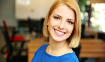 Woman in blue blouse smiling after dental services