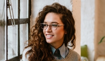 Young woman with glasses sitting at table by window