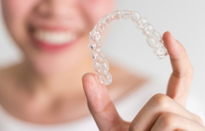 Person holding a SureSmile clear aligner in their hand