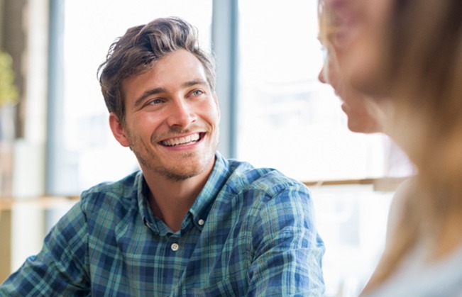 man smiling while talking to friend   