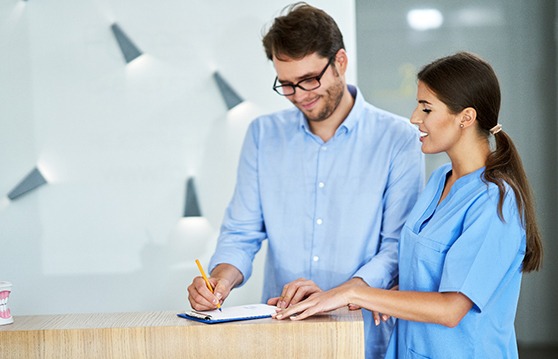 Dental receptionist helping patient fill out forms in lobby