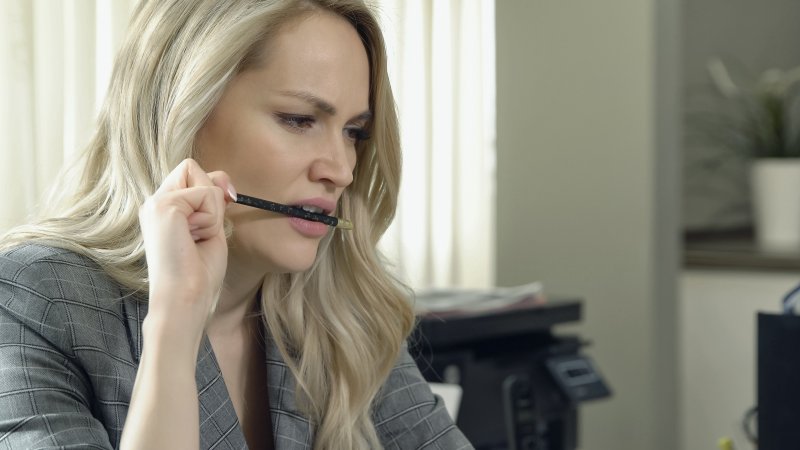 A woman biting a hard object, one of the bad habits to avoid with dental implants