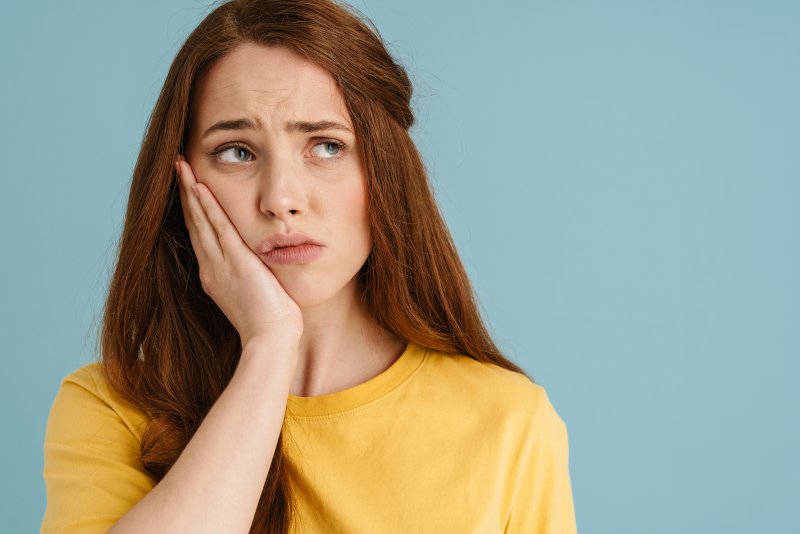 Patient holding their cheek due to dry socket